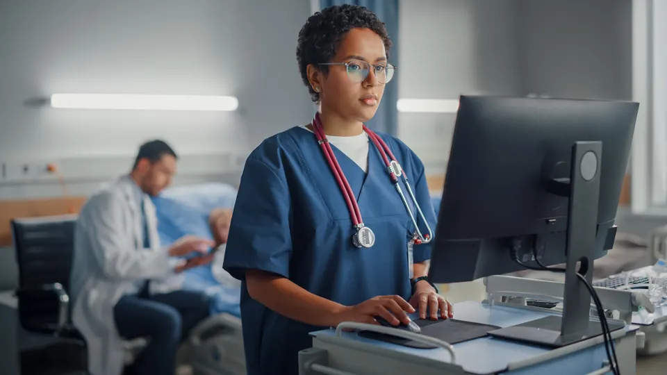 A hospital nurse working at a computer on the ward
